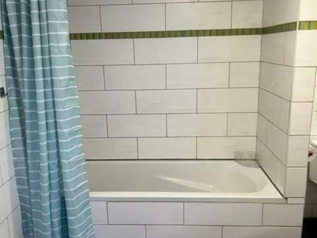 a bath tub with a blue shower curtain in a bathroom at Lovely holiday home in Gouvy with sauna in Gouvy