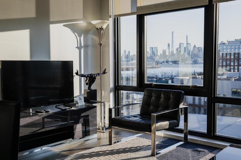 sala de estar con silla y ventana grande en Dharma Home Suites Hoboken, en Hoboken