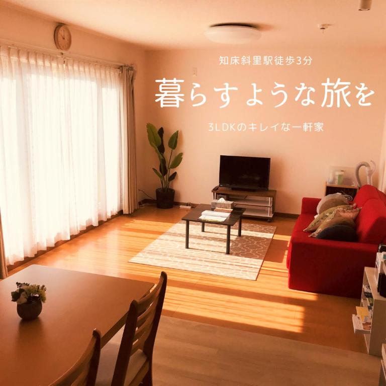 a living room with a red couch and a table at Okhotsk House Shari in Shari