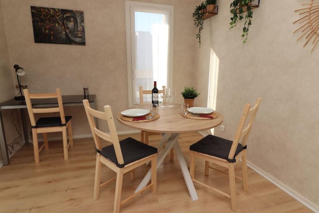 - une table à manger avec 2 chaises et une bouteille de vin dans l&#39;établissement Votre confort la Cosy Cocoon, à Courcouronnes