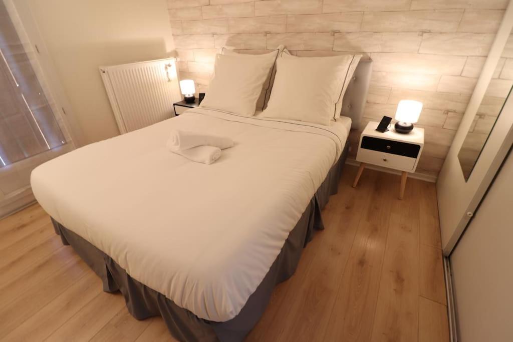 - une chambre dotée d&#39;un grand lit avec des draps et des oreillers blancs dans l&#39;établissement Votre confort la Cosy Cocoon, à Courcouronnes
