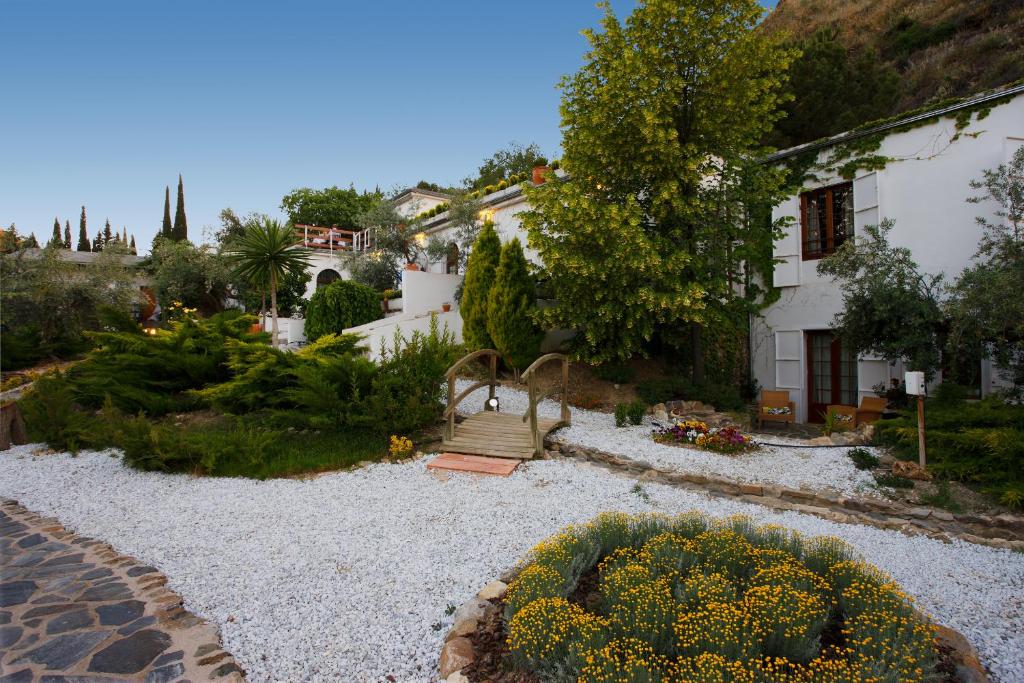un jardín con una casa y un jardín con flores amarillas en La Almunia del Valle, en Monachil