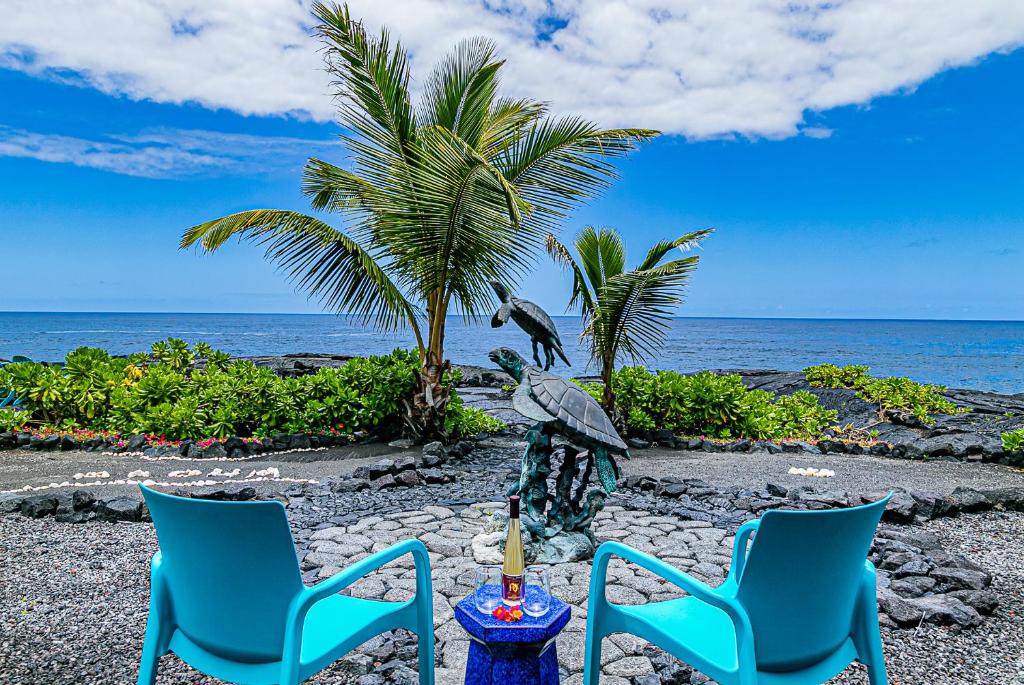 凱阿奧的住宿－Paradise Breeze Retreat- Absolute Oceanfront with Hot Tub!，海滩上的两把蓝色椅子和蜡烛
