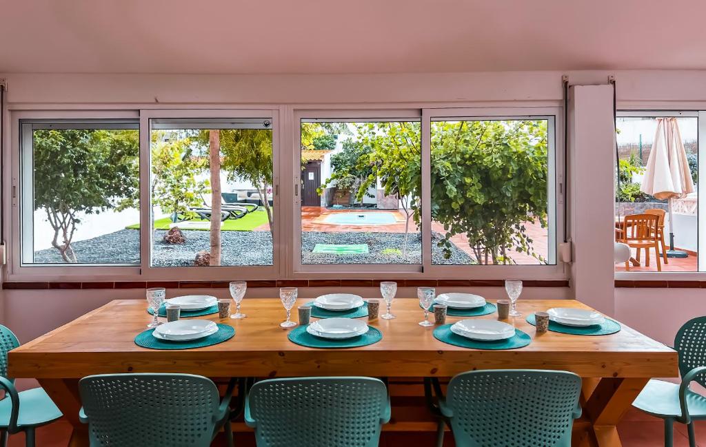 una mesa de madera con sillas alrededor en una habitación con ventanas en Villa Paraíso, en Corralejo