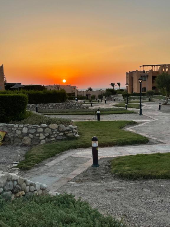 una puesta de sol sobre un parque con un camino de piedra en La hacienda Luxurious chalet with sea view garden 805, en Ras Sedr