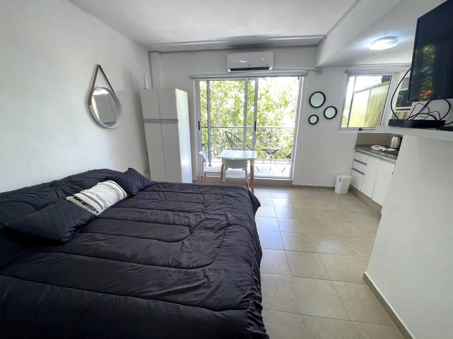 1 dormitorio con cama negra y cocina en Agradable monoambiente en Urquiza- Incas1 en Buenos Aires