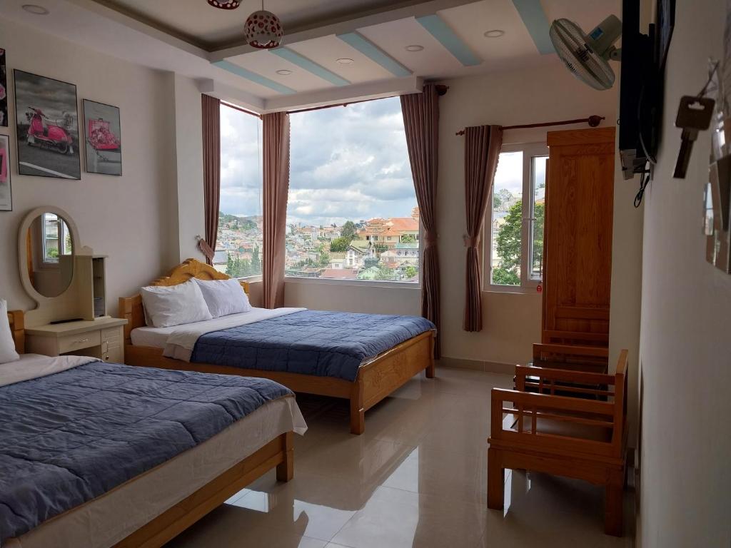a hotel room with two beds and a large window at Cam Ly Homestay in Da Lat
