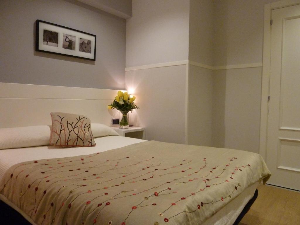 1 dormitorio con 1 cama y un jarrón de flores en Pensión Gárate, en San Sebastián