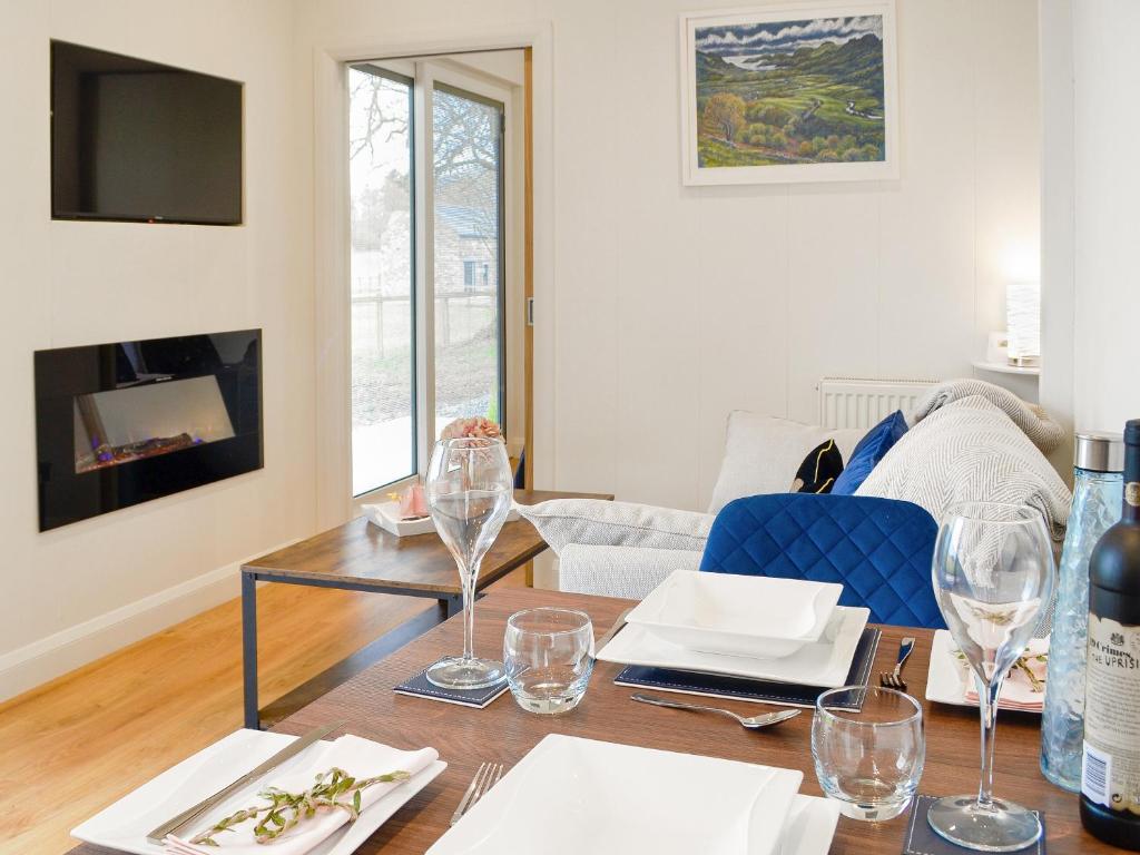 ein Wohnzimmer mit einem Tisch und Weingläsern in der Unterkunft Lime Tree Lodge in Castle Douglas