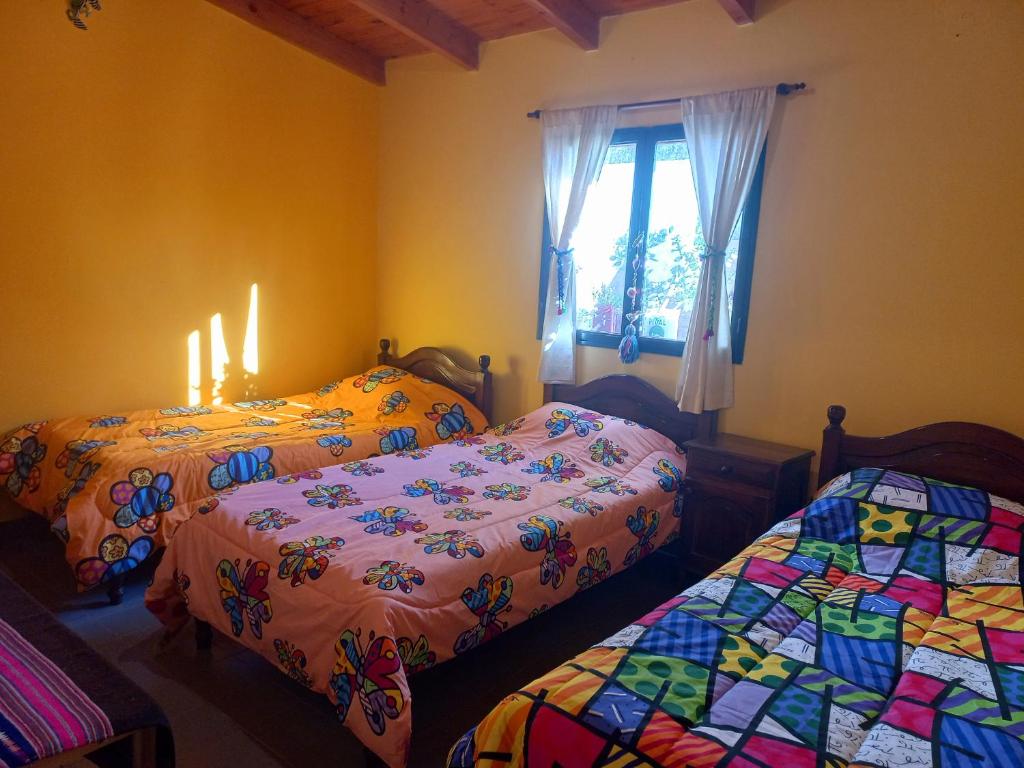 two beds in a room with candles and a window at Casa Munay in Maimará