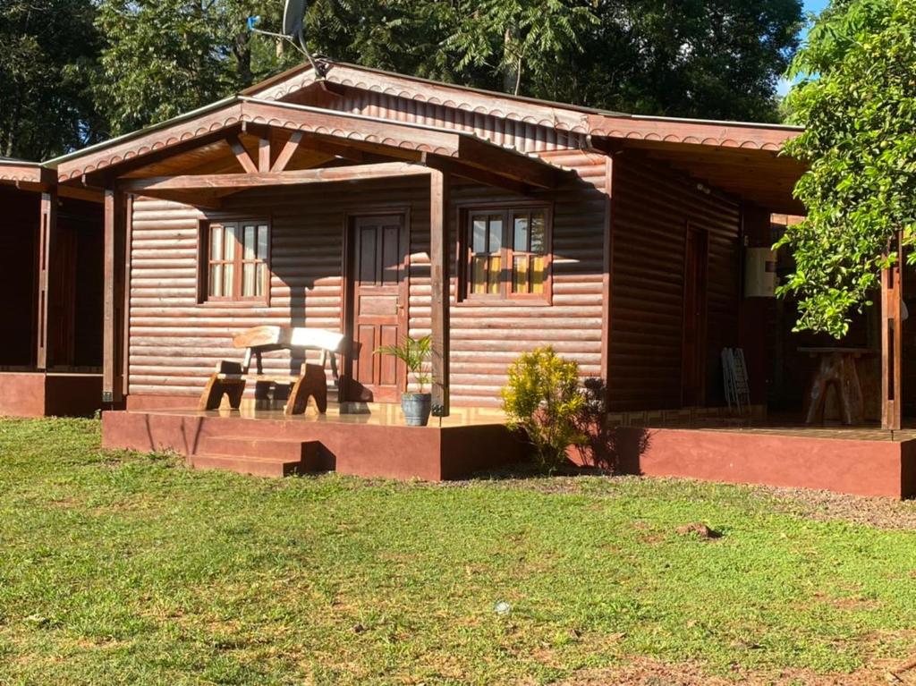 Una cabaña de madera con un porche, una mesa y sillas. en Los Pioneros, en Puerto Iguazú