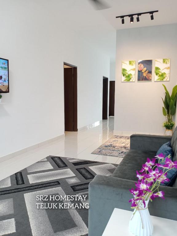 a living room with a couch and a vase of flowers at Srz Homestay Teluk Kemang PD in Port Dickson