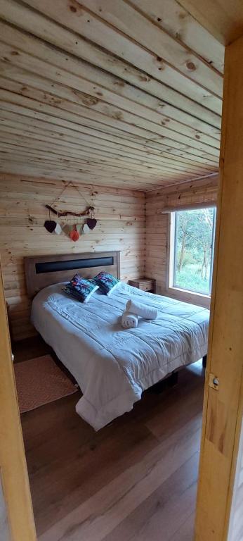 ein Schlafzimmer mit einem Bett in einem Blockhaus in der Unterkunft Cabaña La Troya in Cochamó