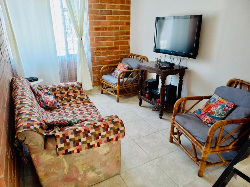 een woonkamer met een bank en stoelen en een tv bij Casa completa amoblada Paipa con tres alcobas in Paipa