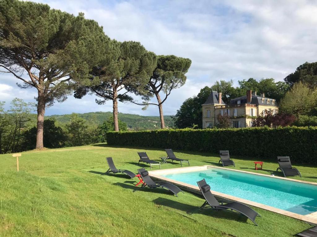 une piscine avec des chaises et une maison en arrière-plan dans l'établissement Gîte La Roque-Gageac, 5 pièces, 8 personnes - FR-1-616-1, à La Roque-Gageac