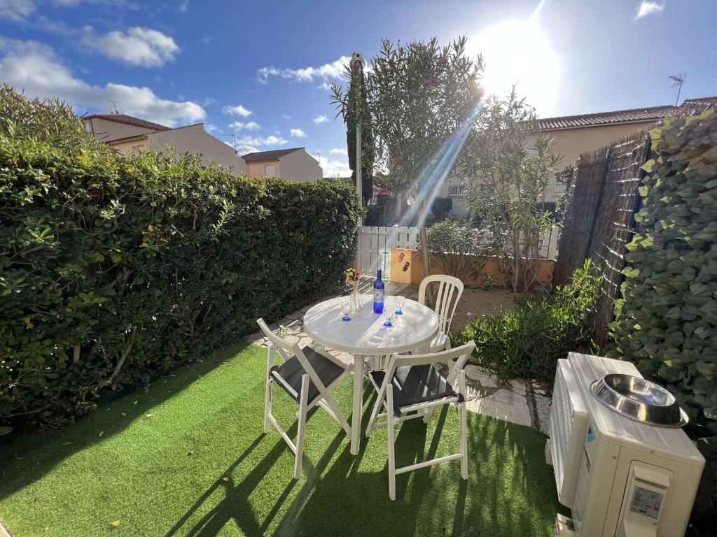 een tafel en stoelen in een achtertuin met een sprinkler bij Appartement Valras-Plage, 2 pièces, 4 personnes - FR-1-701-55 in Valras-Plage