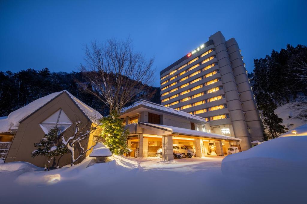 un hotel en la nieve frente a un edificio en Yumoto Kissho, en Osaki