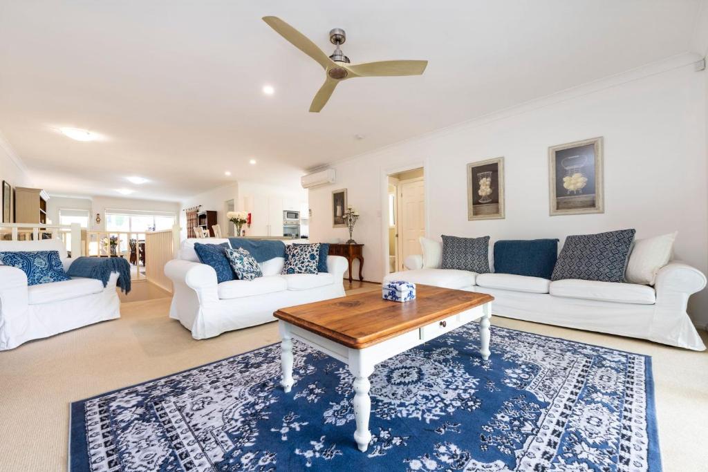 una sala de estar con sofás blancos y una mesa. en Muriels Place in Corlette Port Stephens, en Corlette