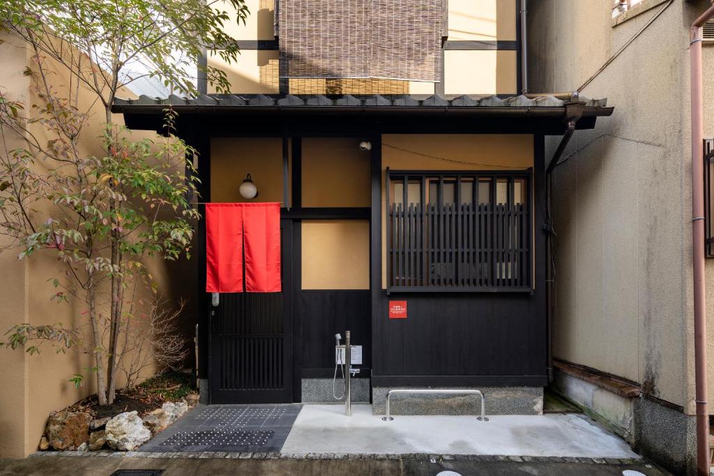 a black door with a red flag on it at 龍馬坂荘：1日1組限定・東山清水のてっぺんの小さなお宿、わんこと一緒に。 in Kyoto