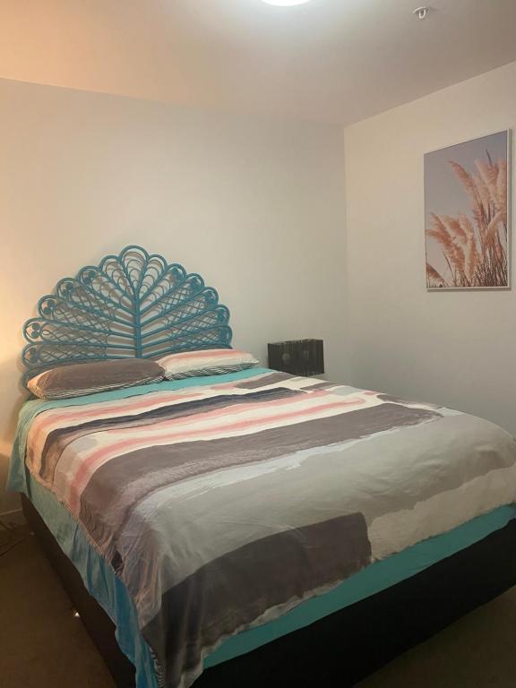 Bett mit blauem Kopfteil in einem Schlafzimmer in der Unterkunft Bayside Melbourne Apartment in Melbourne