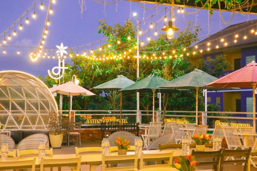 a patio with tables and chairs with lights and umbrellas at Hotel Roditha Banjarbaru in Banjarbaru