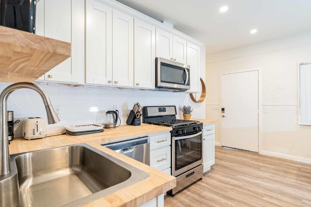 a kitchen with white cabinets and a stainless steel sink at Newly Remodeled 2B1B House on Historic Route 66 in Glendora