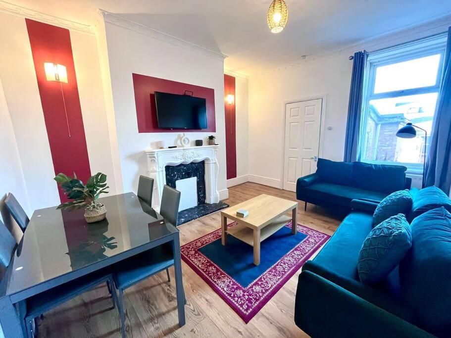 a living room with a blue couch and a fireplace at 3 bedroom house near the city in Gateshead