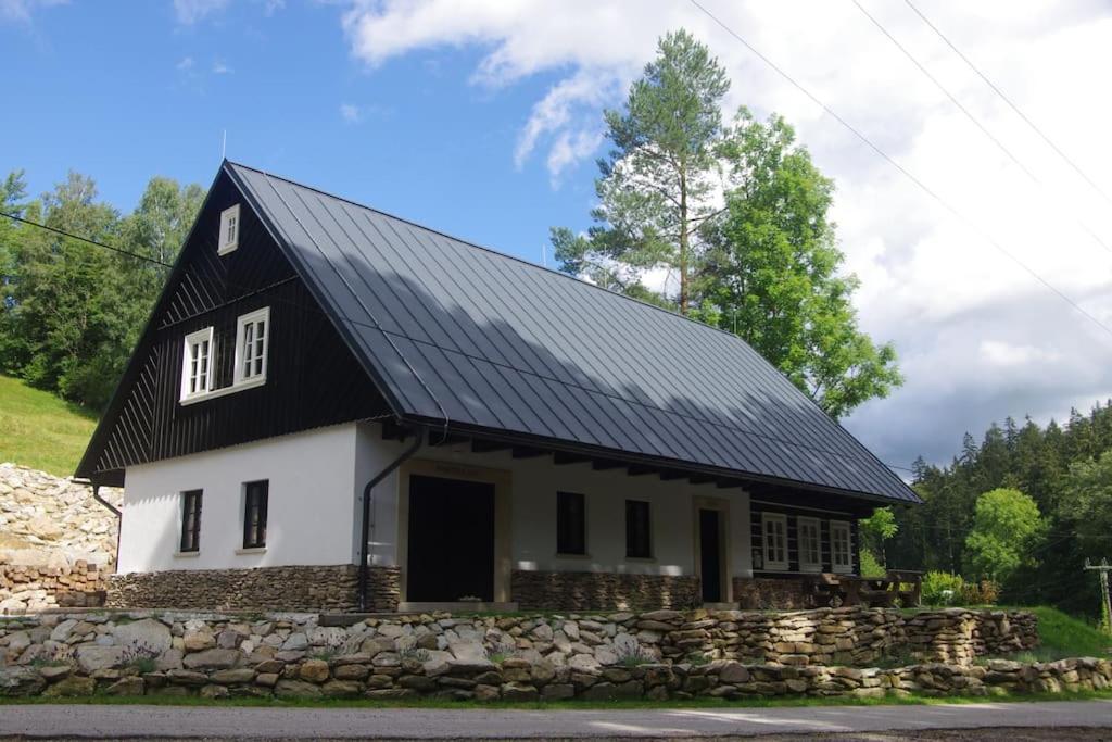 una casa con techo negro y pared de piedra en Horská roubenka František Kvíz en Dolni Dvur