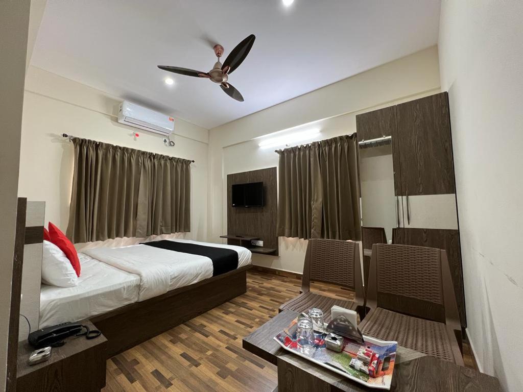 Hotel JP Grand في بانغالور: غرفة نوم بسرير ومروحة سقف