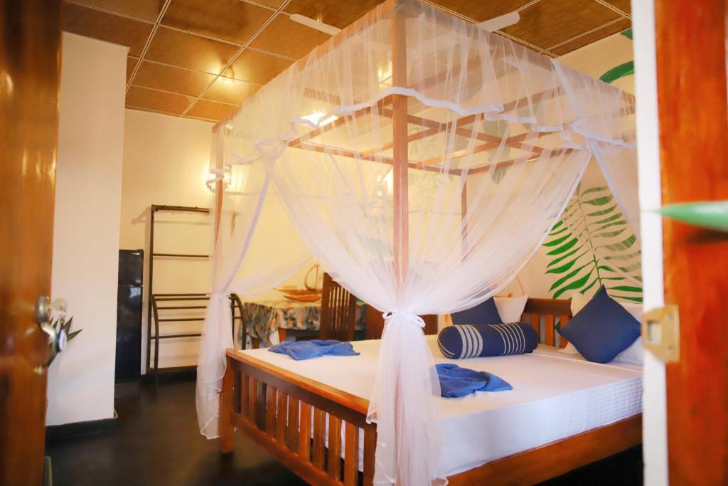 a bedroom with a canopy bed with blue pillows at Ruwan Jungle Homestay in Mirissa