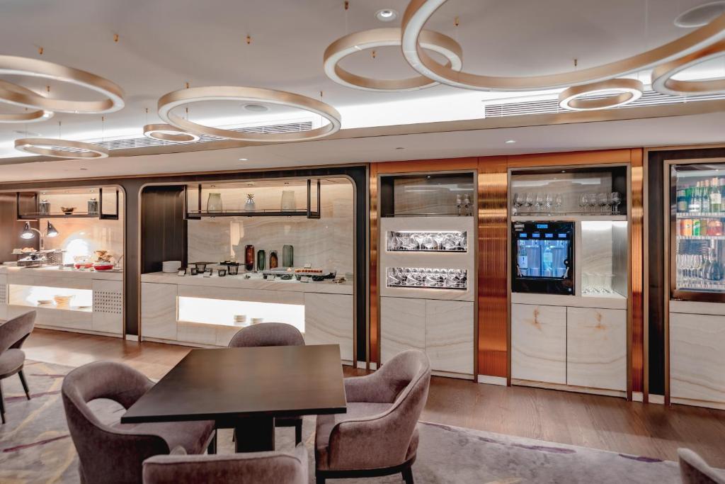 A dining area with a small table, upholstered chairs and built-in beverage displays.