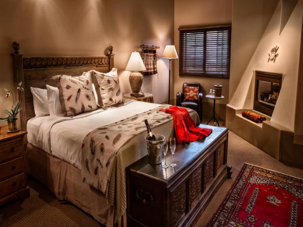 a bedroom with a bed and a dresser and a fireplace at The Hacienda & Spa in Santa Fe