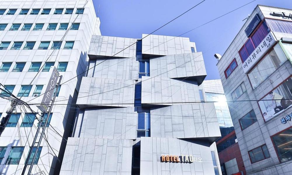 wysoki szklany budynek przed budynkiem w obiekcie Hotel TAO w Seulu