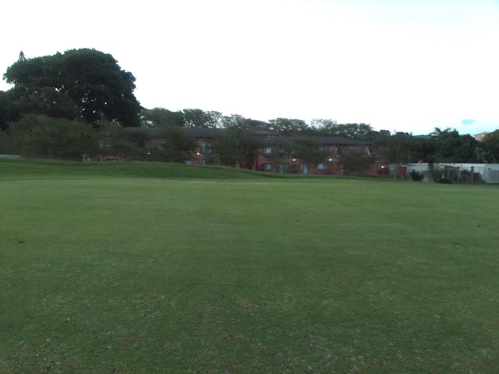 a large green field with houses in the background at Golf view place in Empangeni