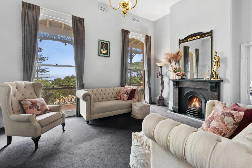 a living room with two couches and a fireplace at Pelicans at the Ozone in Queenscliff