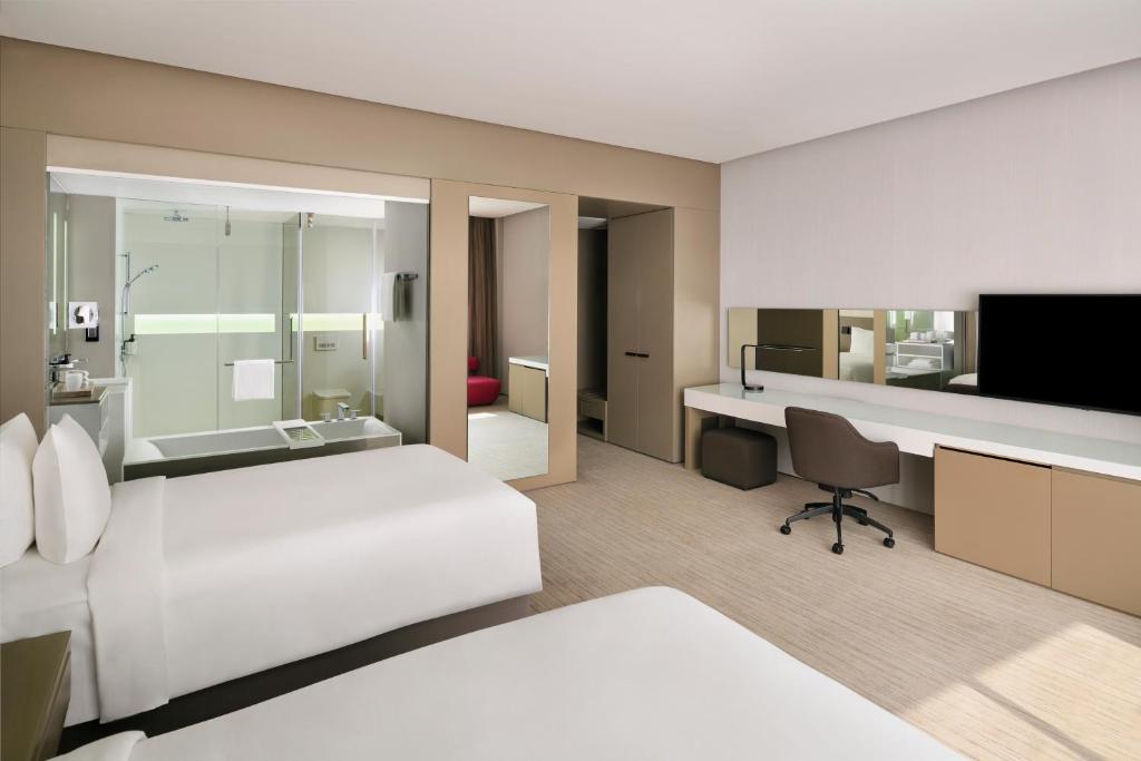 a hotel room with two beds and a desk and a television at InterContinental Dubai Marina by IHG in Dubai
