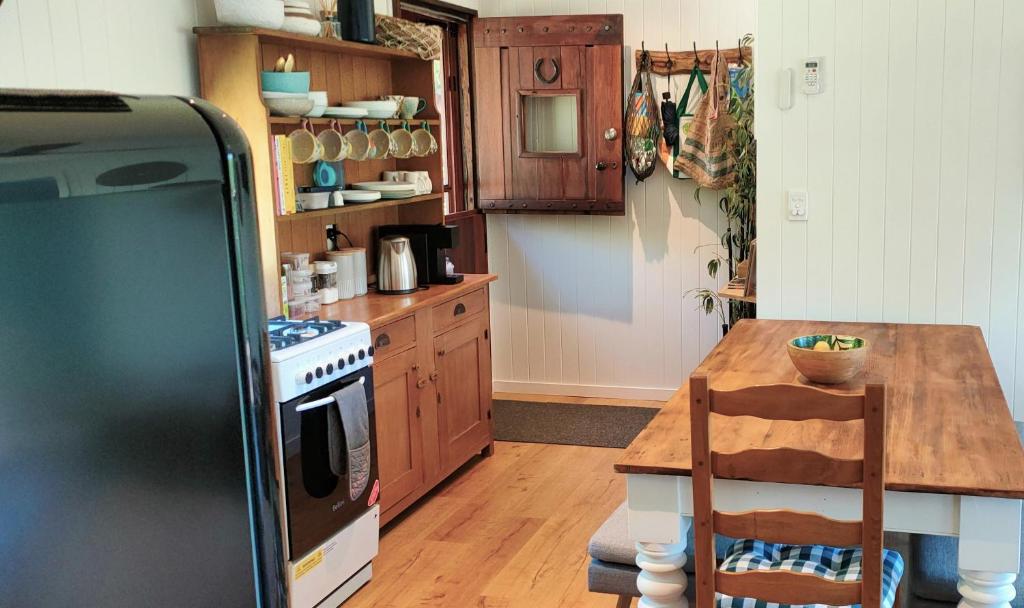 cocina con mesa de madera y nevera en Woodmans Cottage 24, Gold Coast Hinterland en Wongawallan