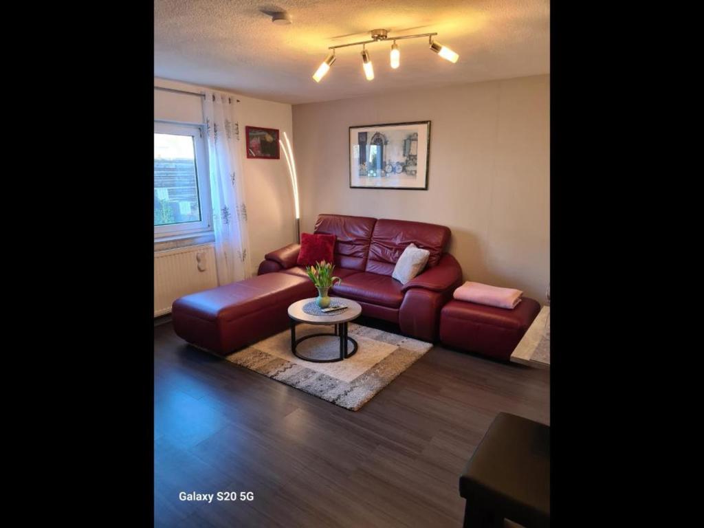 ein Wohnzimmer mit einem roten Sofa und einem Tisch in der Unterkunft NEU! Ferienwohnung Eulennest in Staudernheim