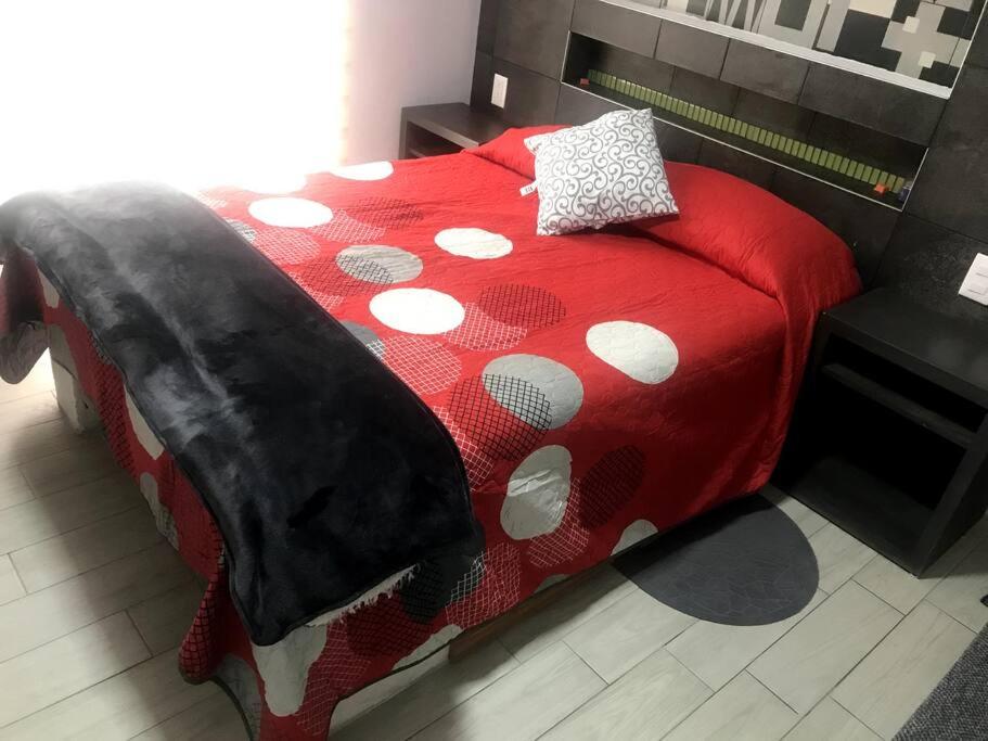 a red bed with a black and white comforter at Habitación Lui confortable moderna con baño privado in Mexico City