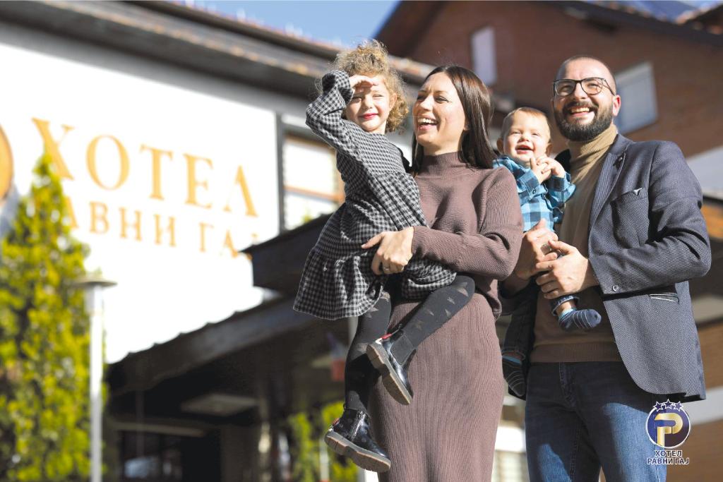 a family walking down the street with a baby at Hotel Ravni Gaj in Knić