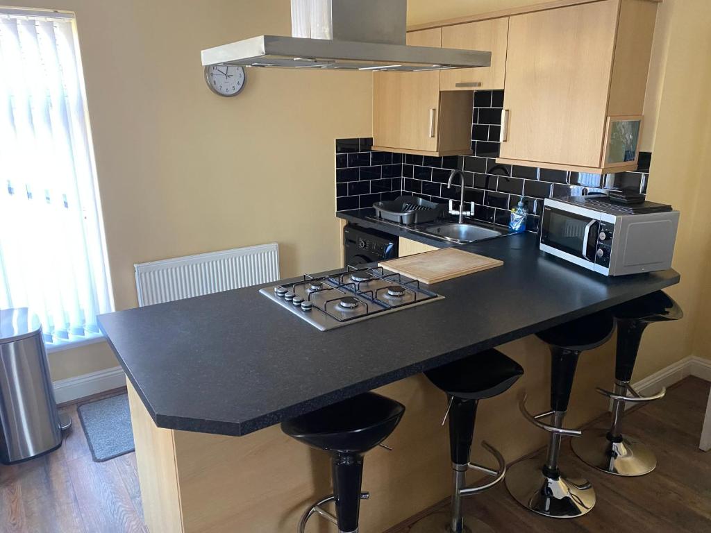 a kitchen with a counter with stools and a microwave at Station House in Merthyr Tydfil