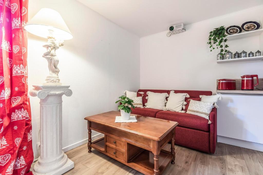 a living room with a red couch and a table at Nid Douillet in Gréolières