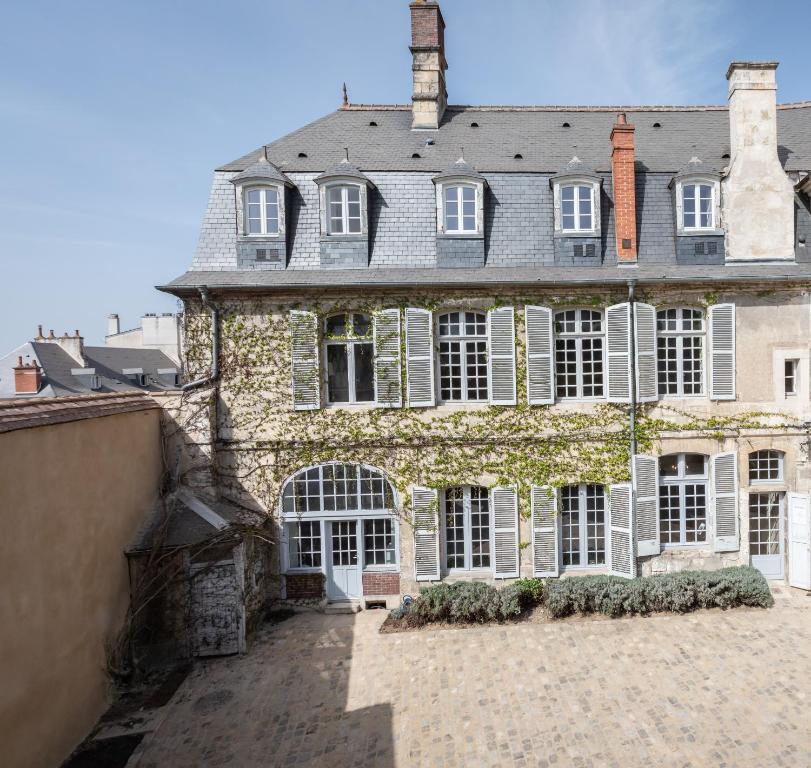 - un grand bâtiment en pierre avec des fenêtres blanches et un toit dans l'établissement L'hôtel de Panette, charpente historique, à Bourges