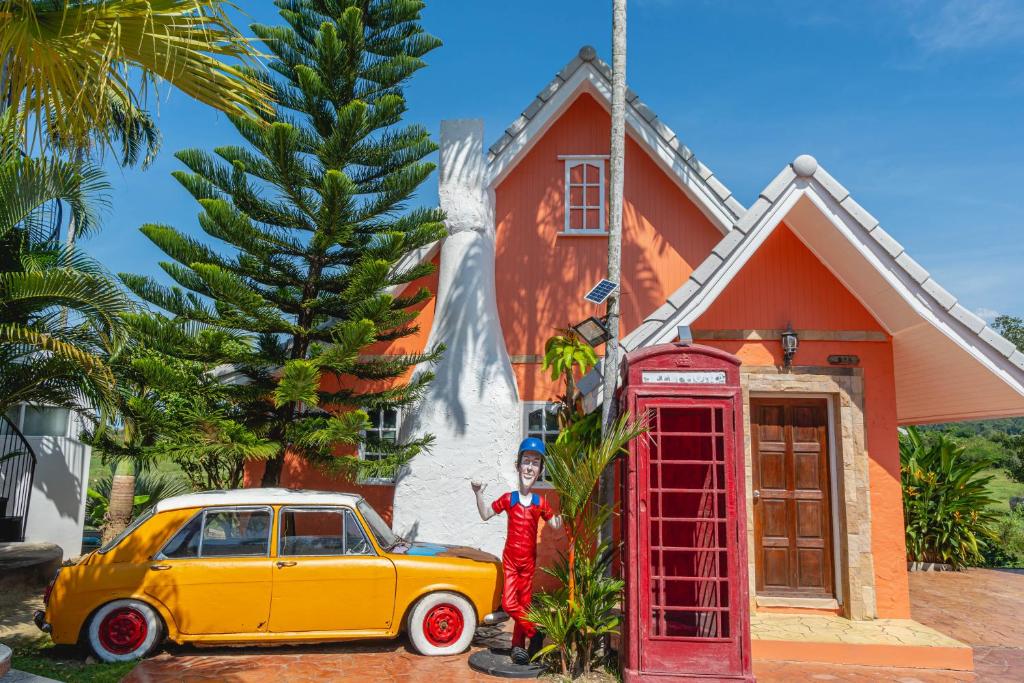 a person standing next to a phone booth and a car at Apinya Resort Bangsarey in Ban Tao Than