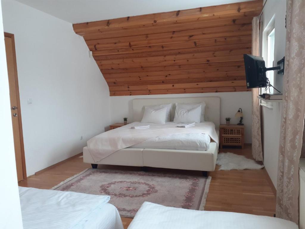 Holiday home Vila Bjelašnica في بييلاشنيتسا: غرفة نوم بسريرين وسقف خشبي