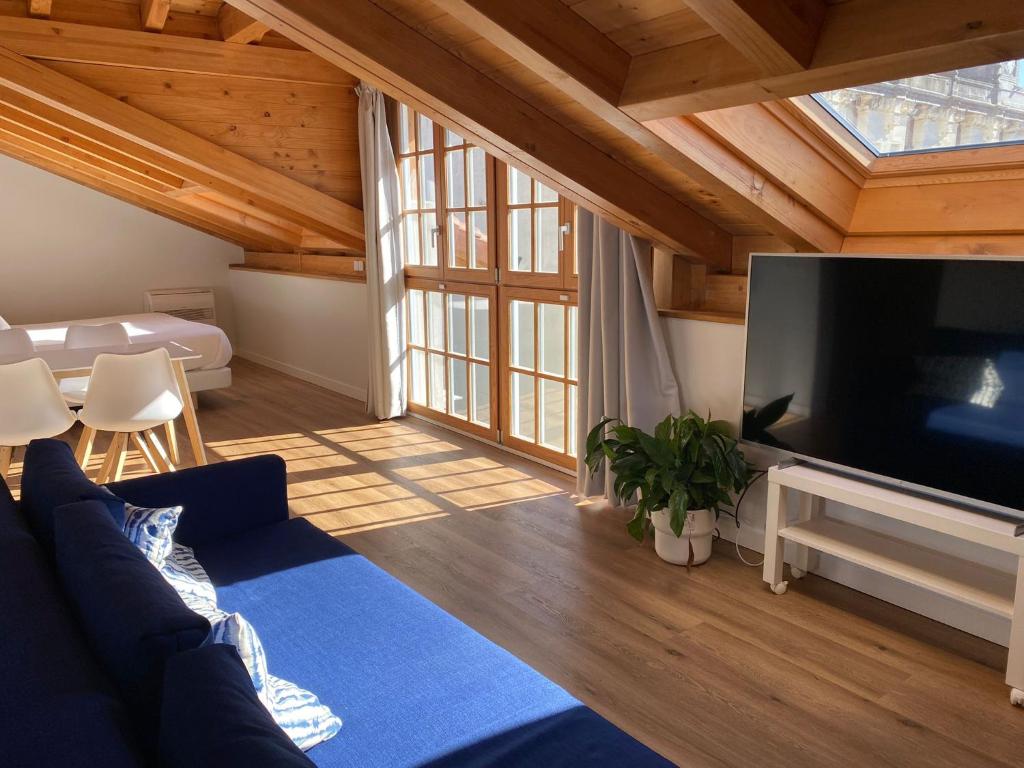 uma sala de estar com um sofá azul e uma televisão de ecrã plano em Apartamentos Mundaka Surf Camp em Mundaka