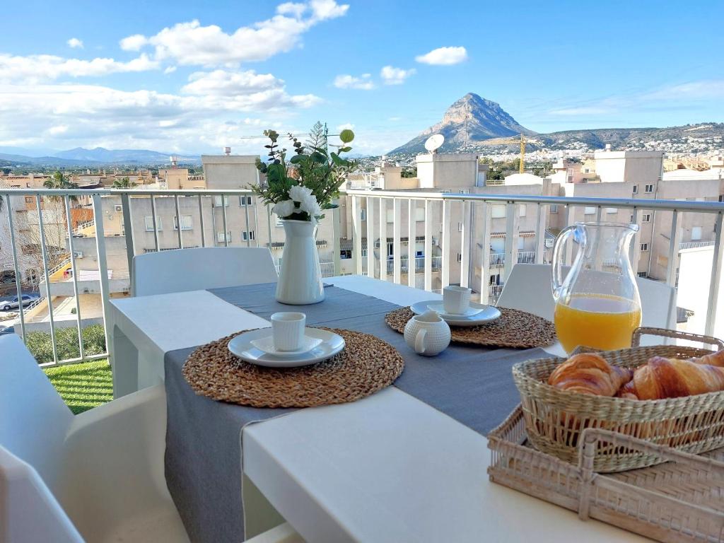 uma mesa com pão e sumo de laranja numa varanda em Apartamentos Strand Jávea em Xàbia