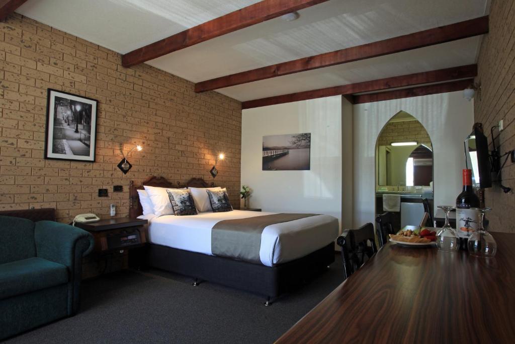 a bedroom with a bed and a desk and a couch at Belltower Motor Inn in Shepparton