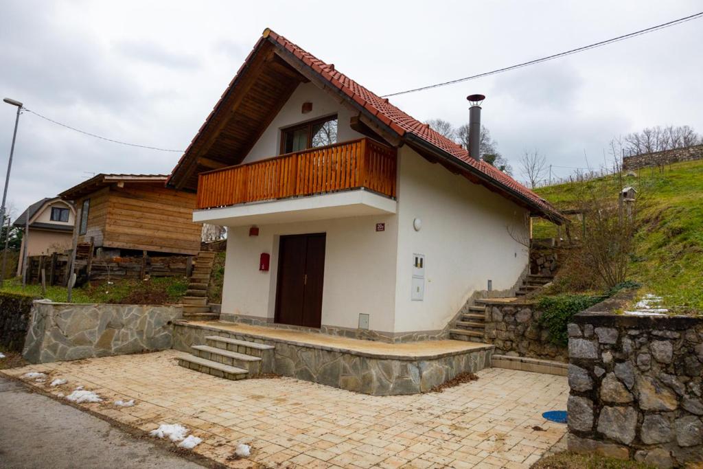 Cette petite maison blanche dispose d'un balcon sur une colline. dans l'établissement Koča na Kučarju / House on a Hill, à Gradac