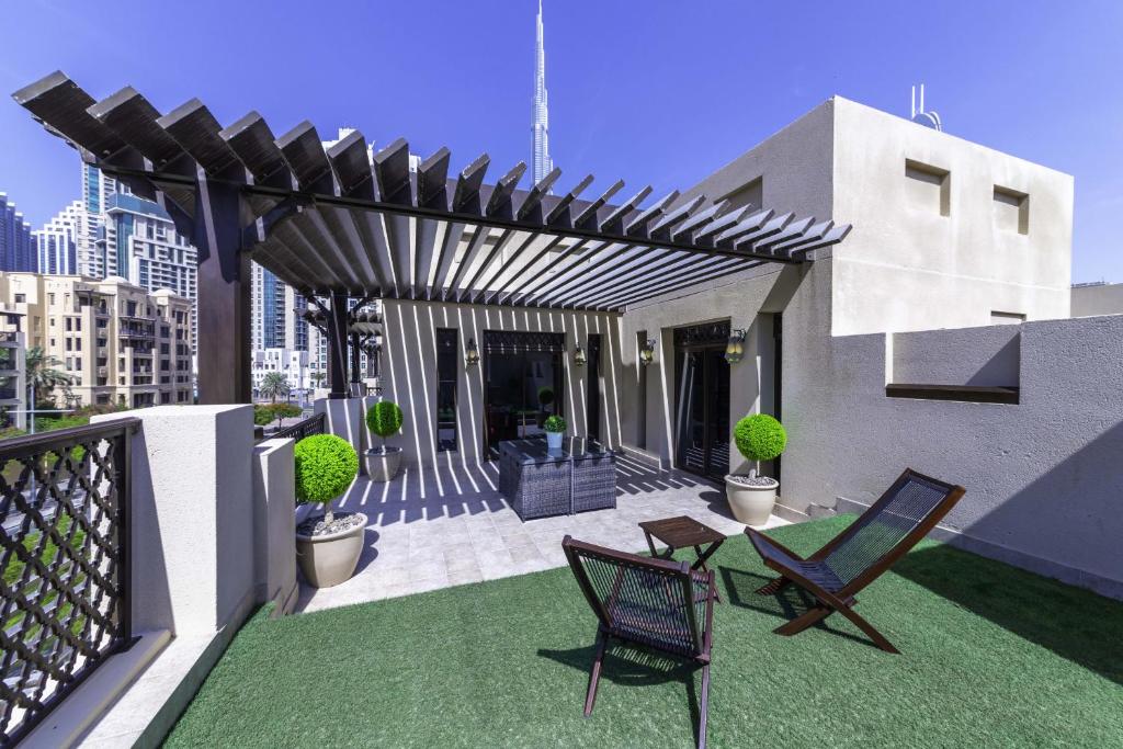 un patio con 2 sedie e un pergolato in legno di Zaafaran Tower 2 - 2BR Apartment - Allsopp&Allsopp a Dubai